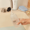 A person filling a Blueland hand soap bottle with water, adding a tablet, then washing their hands with foaming soap