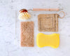 Reusable sponge options like silicone, natural materials, and a scrub brush on white tile
