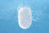 A white effervescent tablet dissolving in water, releasing bubbles and creating a fizzy effect against a blue background.
