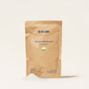 A compostable brown paper bag labeled Oxi Laundry Booster Refills with Spring Bloom and 1 Refill 17.6 oz / 500g stands upright, revealing a small mound of white powder perfect for stain removal.
